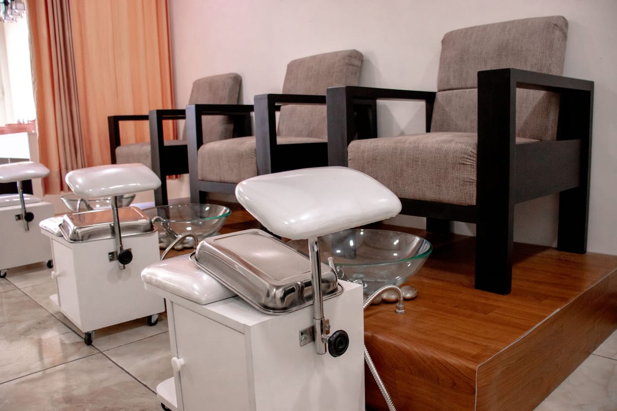Empty pedicure chairs and foot spa basins in a salon